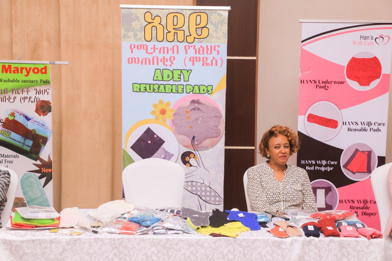 A manufacturer display with packaged reusable pads and an Adey Reusable Pads banner.