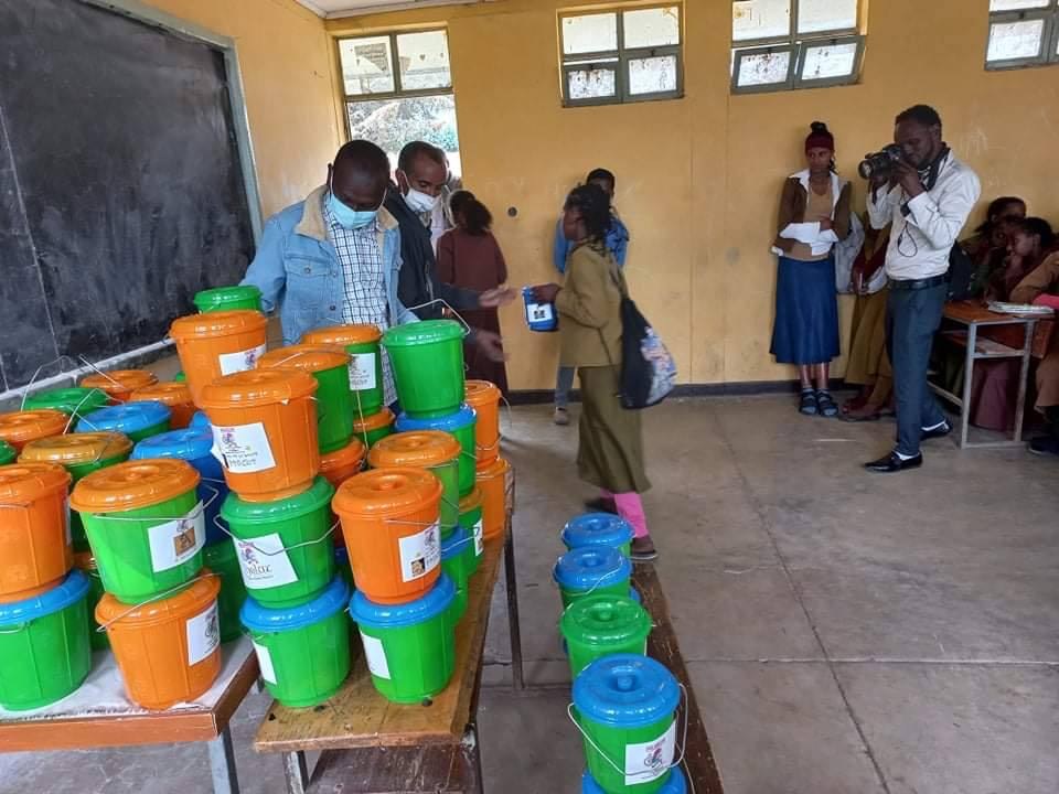 Birqe buckets arranged on classroom desks during a school-based distribution activity.