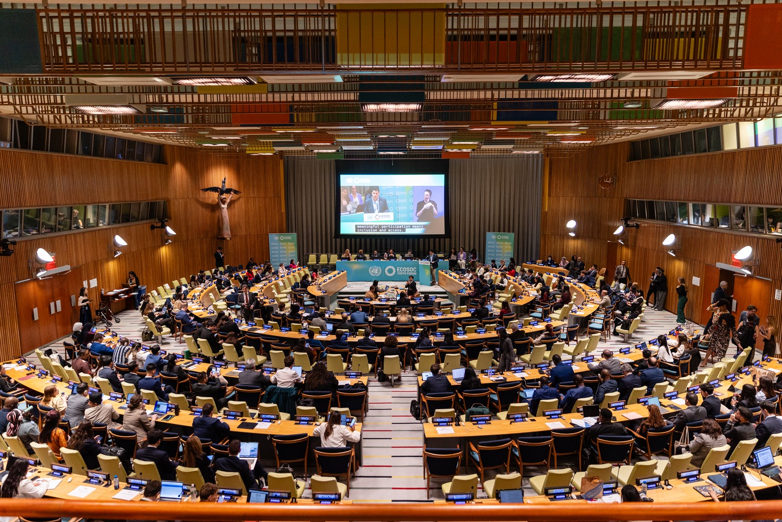 A wide view of delegates and the stage in an ECOSOC Youth Forum conference chamber.