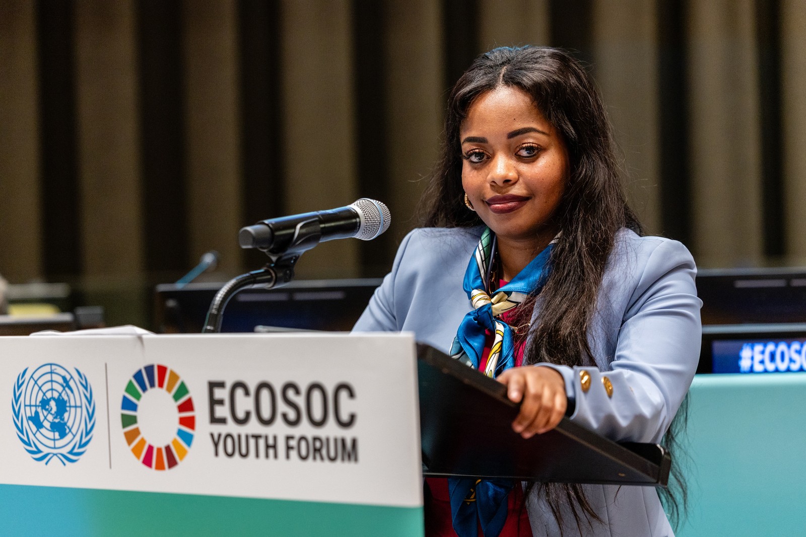A speaker at a lectern carrying ECOSOC Youth Forum branding.